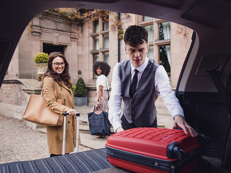 Hotel staff helps two young women bring their luggage inside