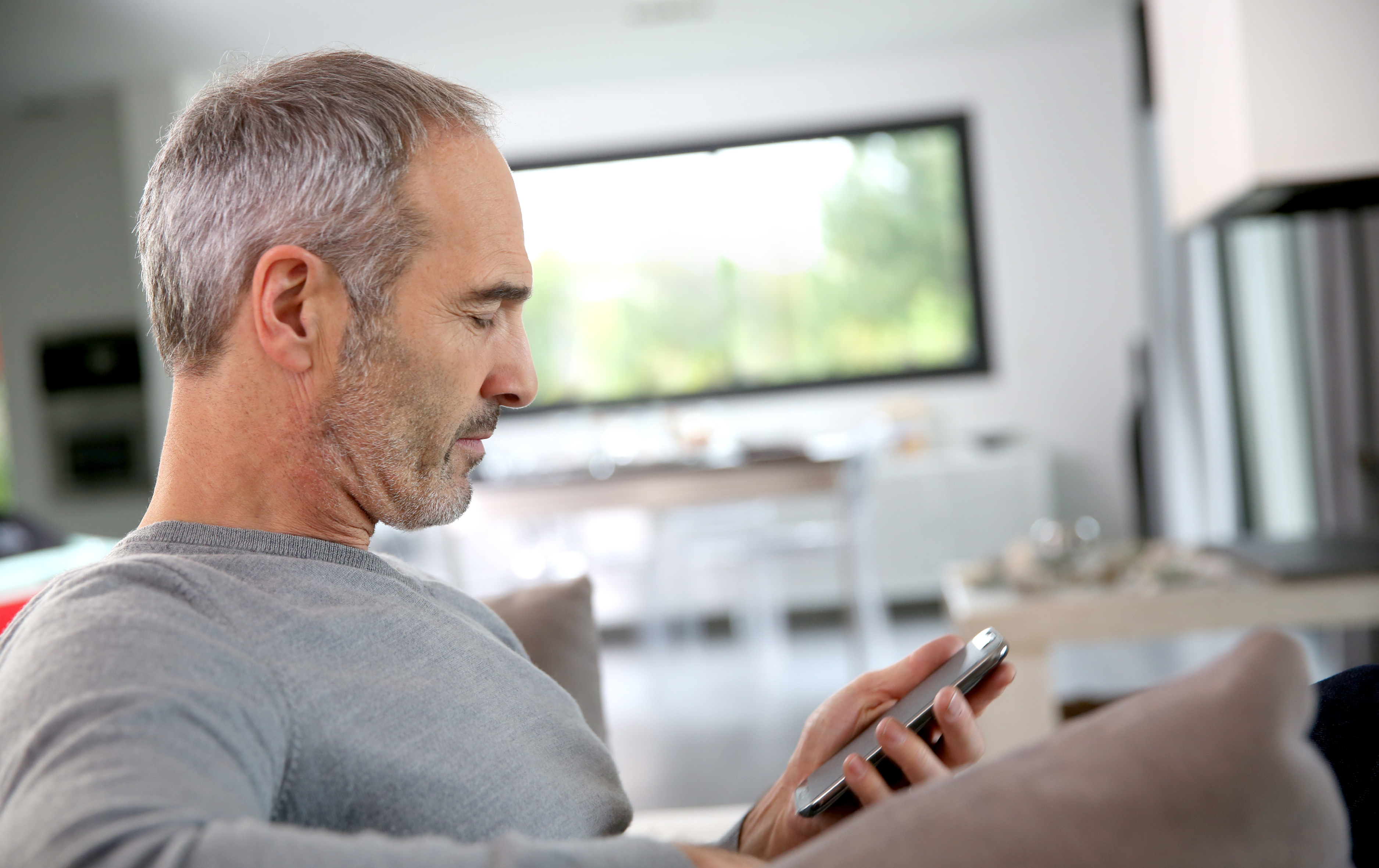 Portrait of man sitting on sofa using his smartphone