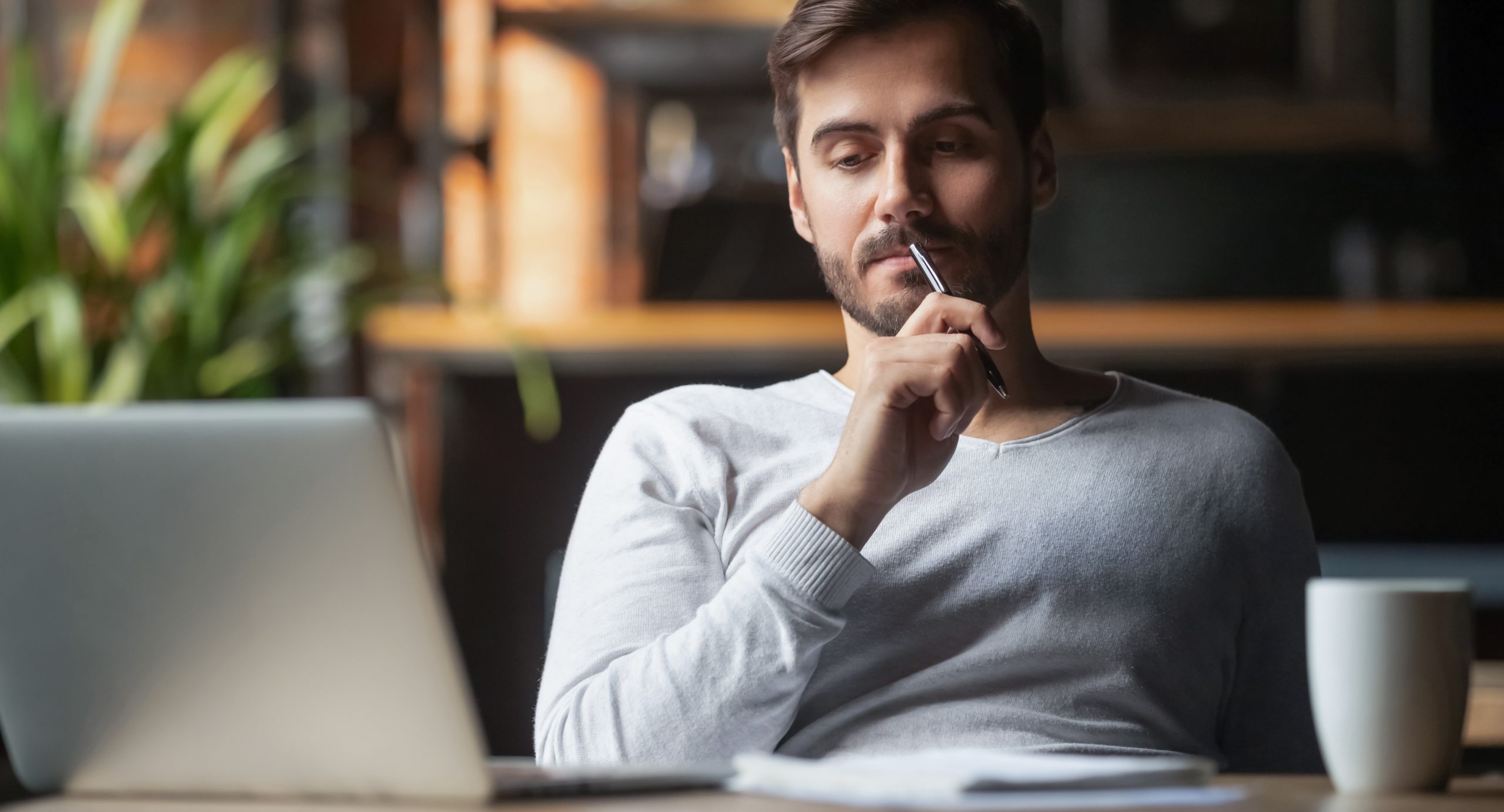 Portrait of thoughtful bearded man in front of his laptop