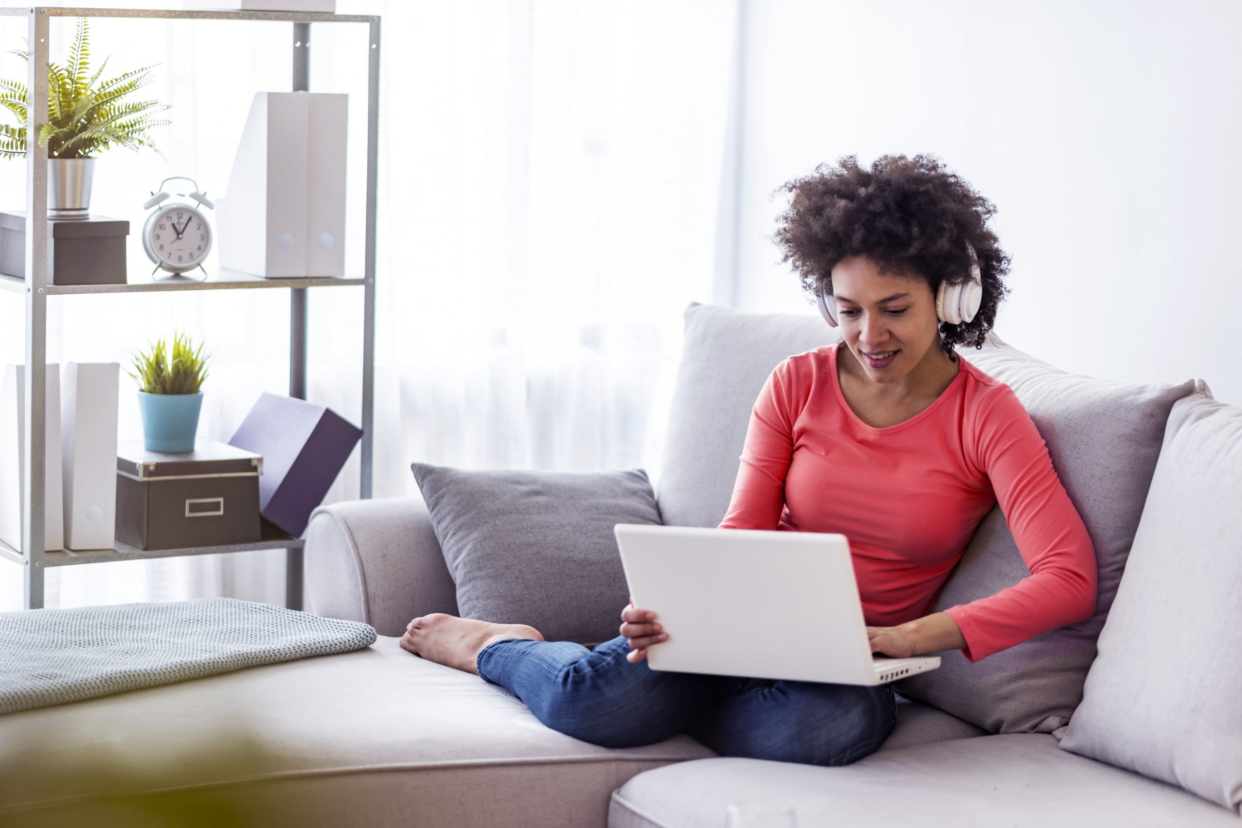 Smiling young woman watching a video with her laptop while sitting on a sofa