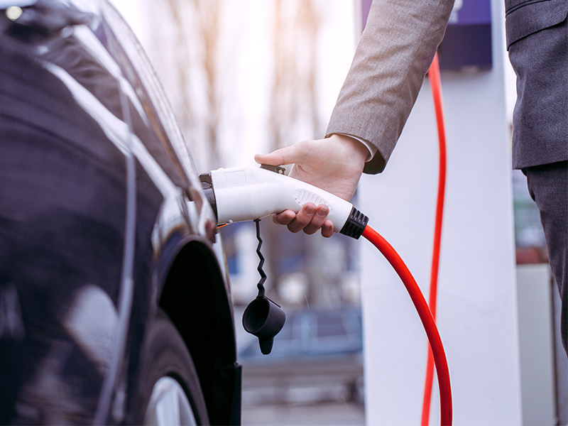 Men charging electric vehicle