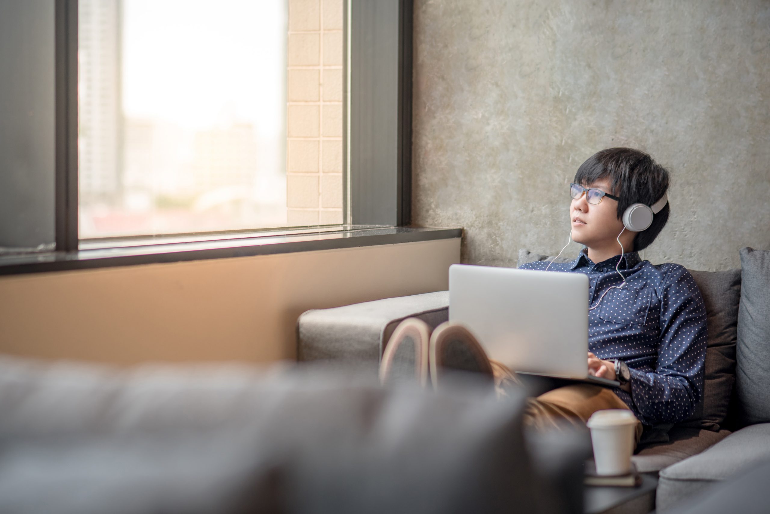 Young man sitting in armchair with a laptop on his lap